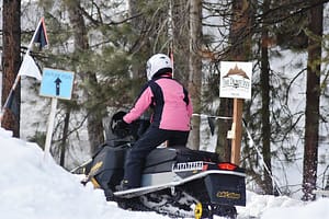 Lady on snowmobile entering trail