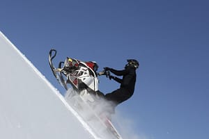 man on snowmobile climbing up hill